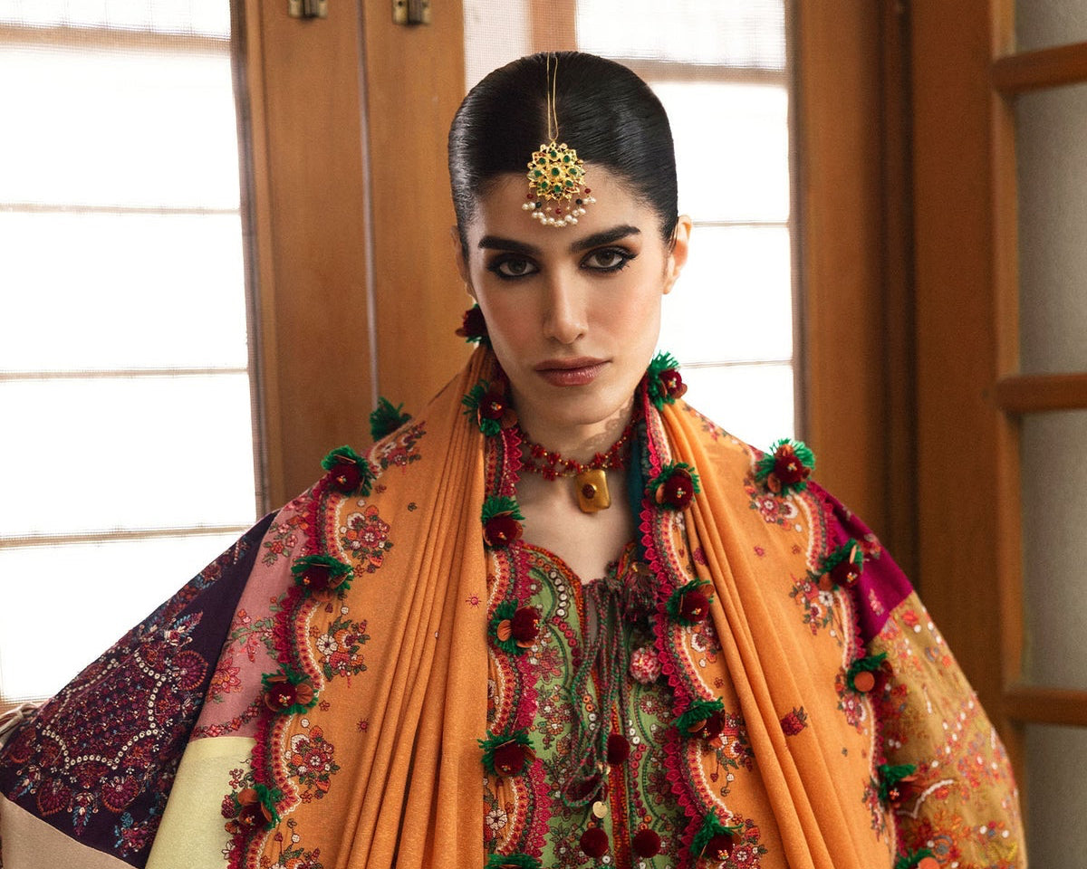 Woman wearing a traditional embroidered outfit with a colorful shawl indoors.